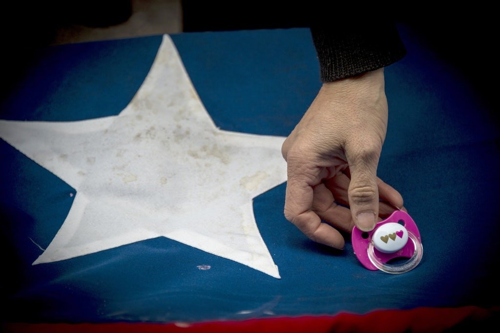 Abortion and Maternal Mortality in Chile A hand holding a pink pacifier above the white star on a Chilean flag.