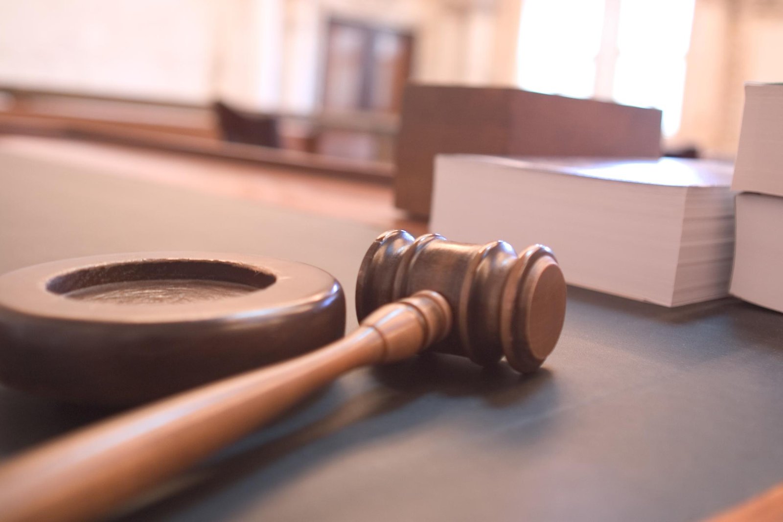 Wooden courtroom gavel and sound block beside books.