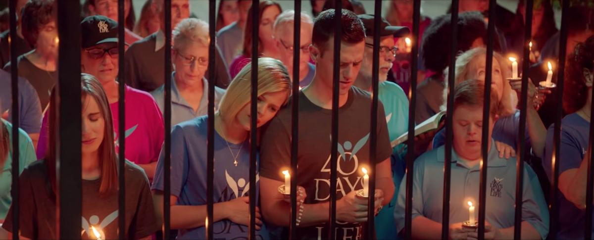 Crisis pregnancy centers and sidewalk counciling People holding candles during a 40 Days for Life prayer vigil behind a metal fence.