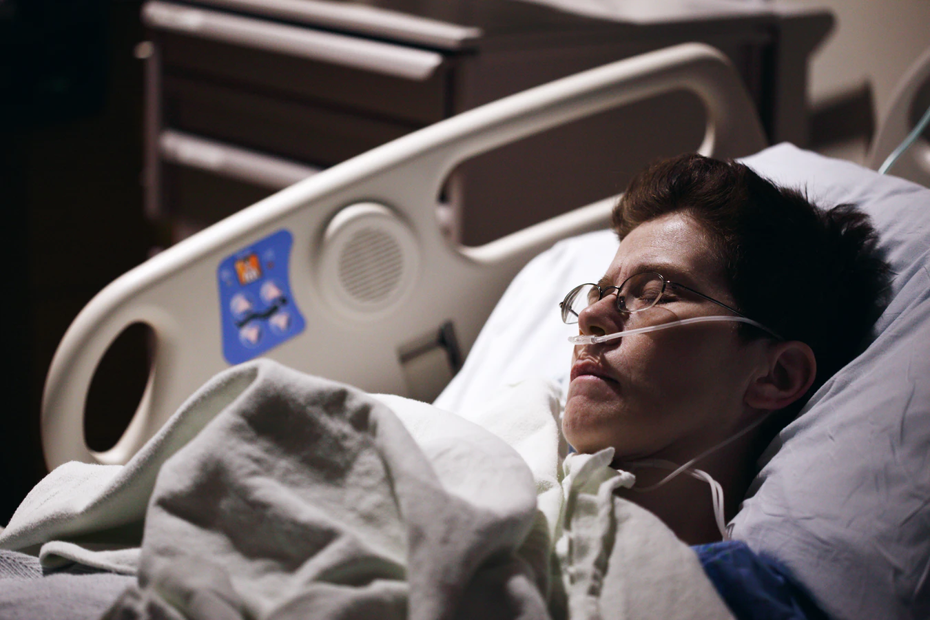 Dehumanization: Can We Rationally Deny The Unborn Personhood? A person resting in a hospital bed with glasses and an oxygen tube.