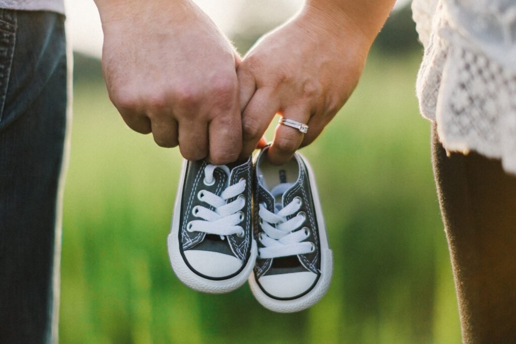 Viability as a Criteria for Personhood Two adults holding hands and a pair of small black-and-white baby shoes outdoors.